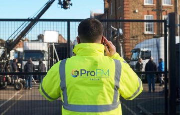 A ProFM security officer monitoring an outdoor media production set with expensive filming equipment behind a fence