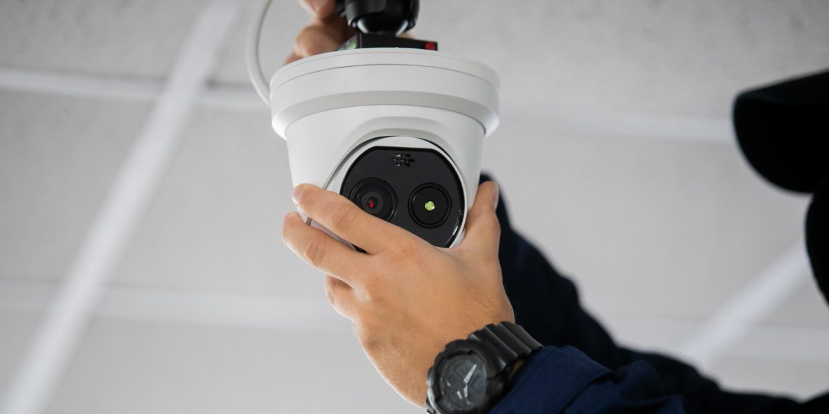 A technician installing a commercial dome CCTV camera onto a ceiling grid for a customised business security system