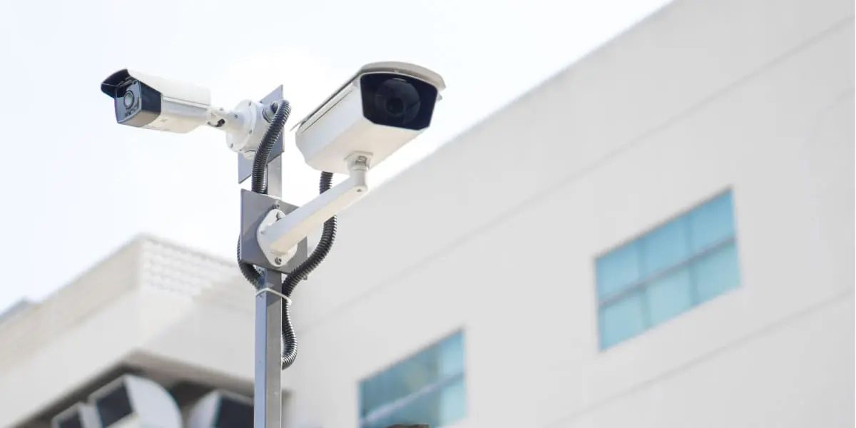 Two commercial CCTV security cameras mounted on an outdoor pole to optimise building surveillance coverage