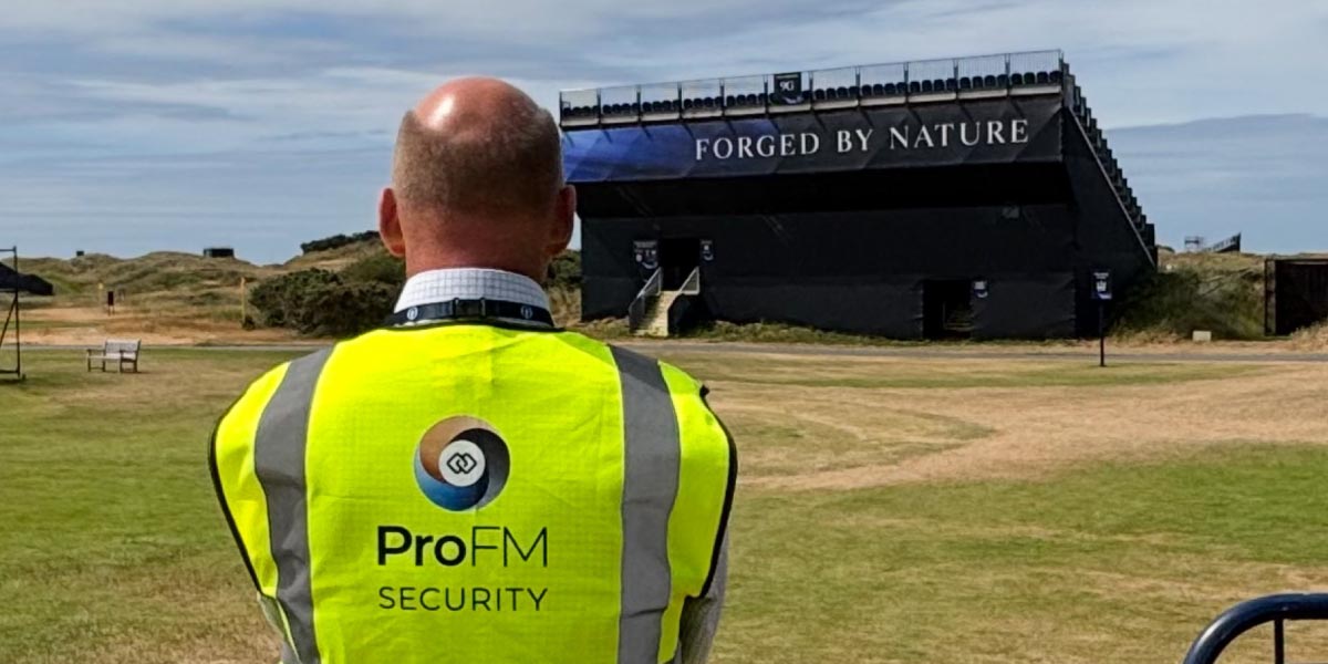 A ProFM security officer in a high-visibility vest looking out toward an outdoor event grandstand