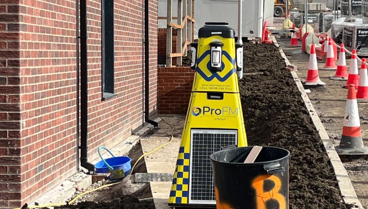 A yellow ProFM VPOD wireless security tower placed next to a new brick building on a housing development site