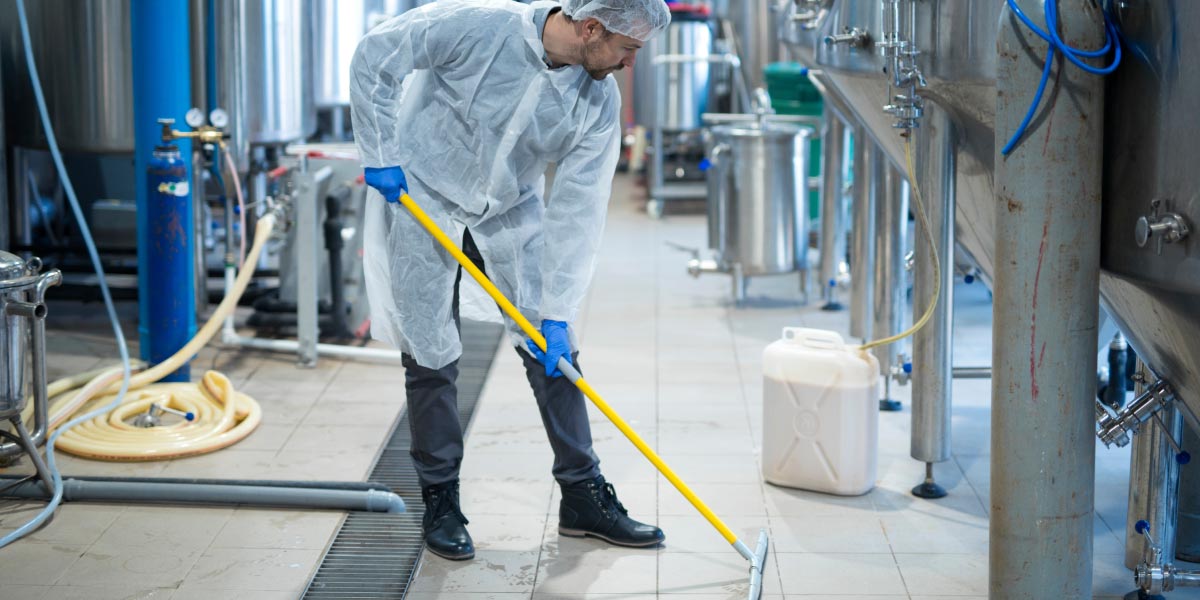 Industrial cleaner carrying out factory floor cleaning and sanitisation within a manufacturing production facility.