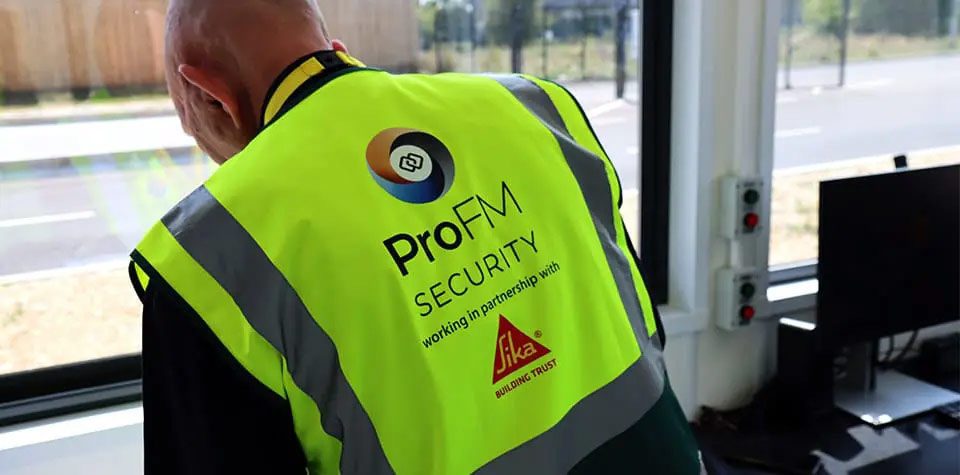 ProFM Security officer monitoring site access and perimeter activity from a gatehouse security control point.