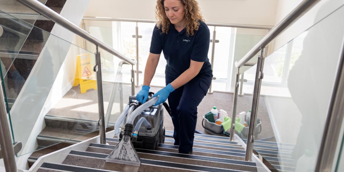 Professional cleaner cleaning stairways and communal areas within a managed residential property.