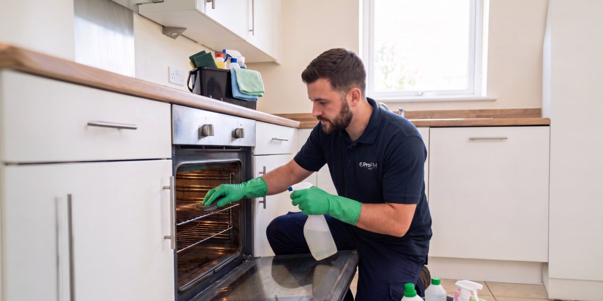 Professional cleaner carrying out end of tenancy kitchen cleaning within a managed residential property.