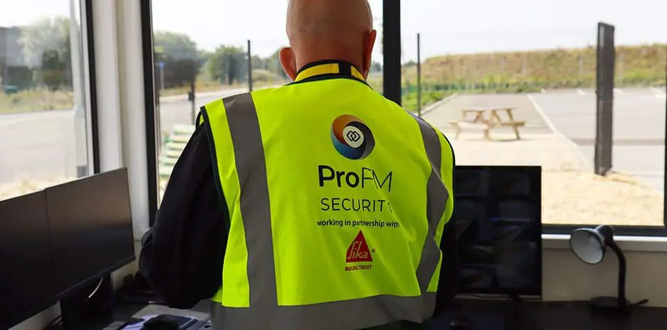 ProFM Security officer monitoring site access and security systems from a gatehouse security control room.