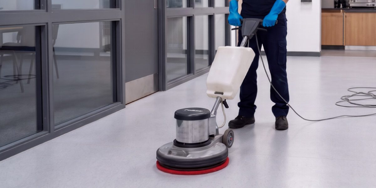 Professional cleaner using a floor polishing machine within a university building as part of a quality-controlled campus cleaning programme.
