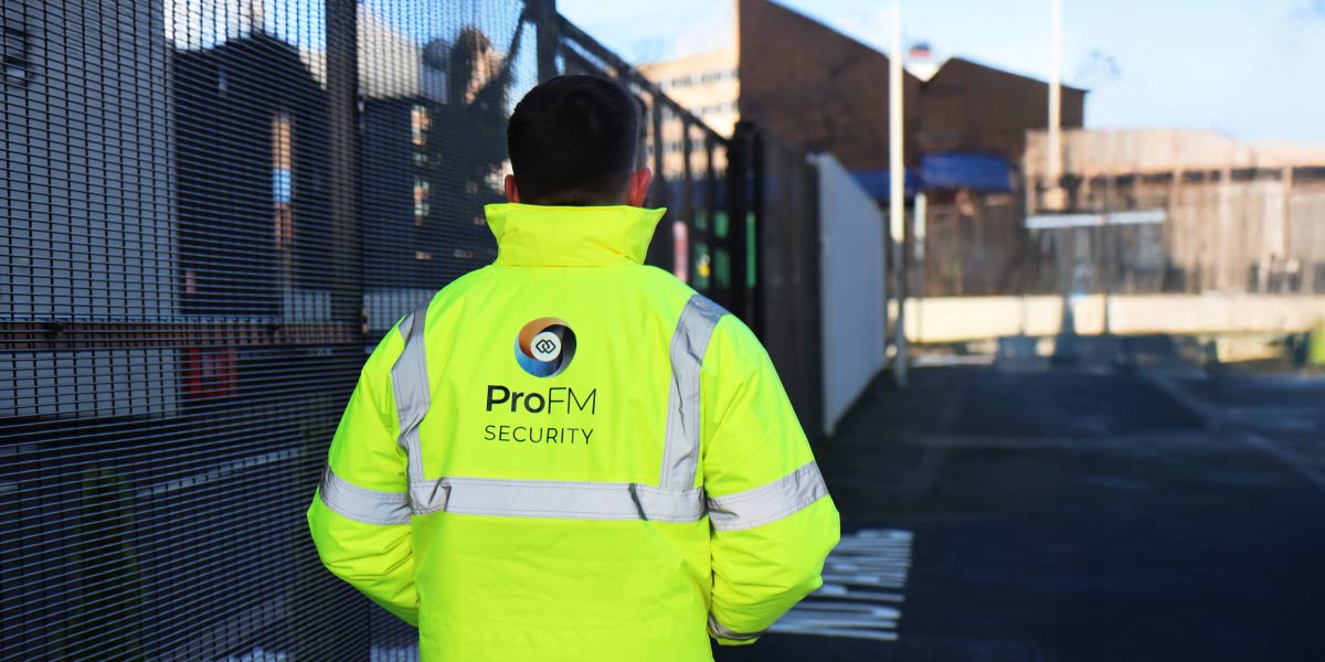 ProFM security officer patrolling a secure site perimeter alongside security fencing as part of a manned guarding service.